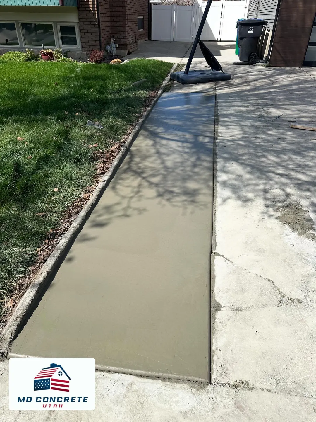 Fresh sidewalk beside a yard by MD Concrete in Utah