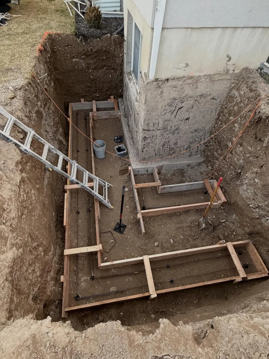 Footing forms beside a basement wall by MD Concrete in Utah